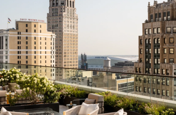 Rooftop terrace at Kamper’s in Detroit featuring elegant lounge seating, lush greenery, and sweeping skyline views including Ford Field and historic downtown buildings.