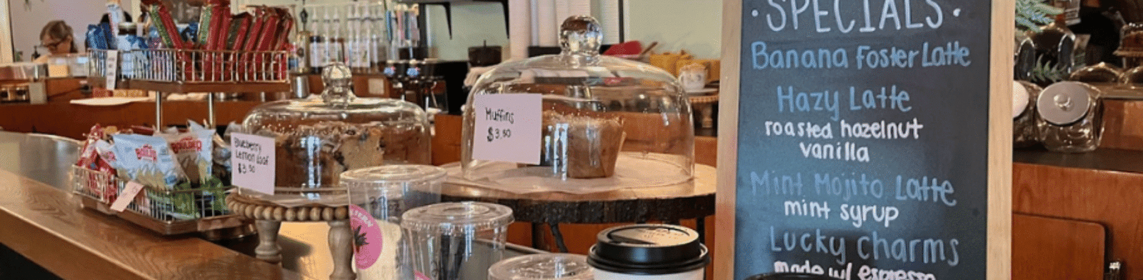 The Fern coffee shop in Royal Oak featuring branded cups, pastry counter, and chalkboard latte specials.