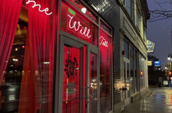 Exterior of Time Will Tell in Detroit at night featuring glowing red neon signage, sheer red curtains, and a moody, intimate cocktail bar entrance along a city street.