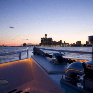 Couple sipping champagne on the deck of a luxury yacht cruising along the Detroit River at sunset, with skyline views in the background.